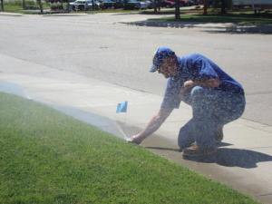 an irrigation contractor is checking a sprinkler head