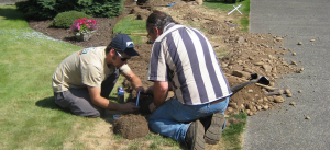 two irrigation repair pros are in the middle of a broken pipe fix